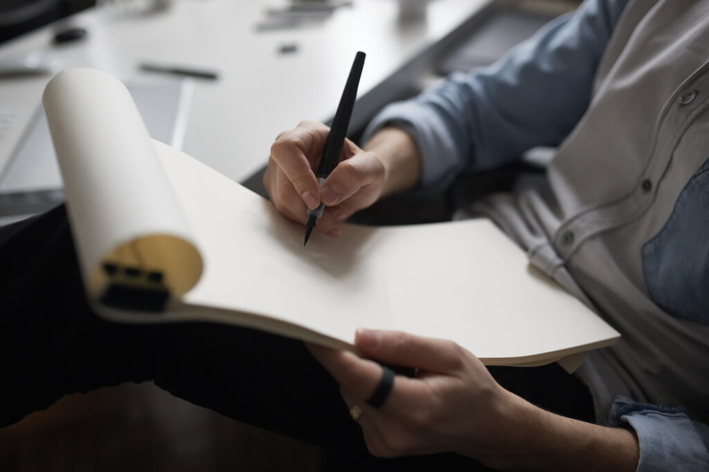 Homem escrevendo e planejando como começar uma empresa, em uma prancheta